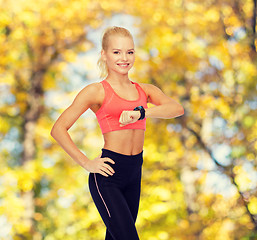 Image showing smiling woman with heart rate monitor on hand