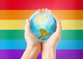 Image showing close up of hands with earth globe over rainbow