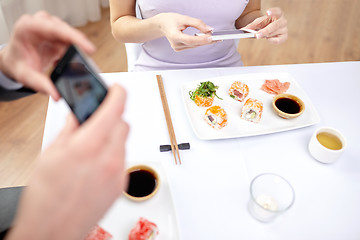 Image showing close up of couple with smartphones at restaurant