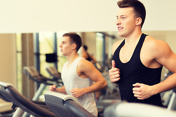 Image showing smiling men exercising on treadmill in gym