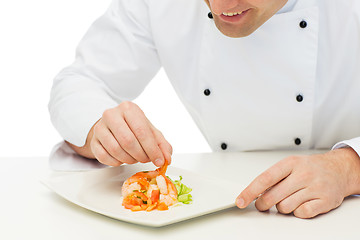 Image showing close up of happy male chef cook decorating dish