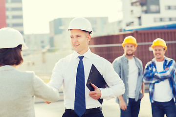 Image showing group of smiling builders in hardhats outdoors