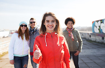 Image showing happy teenage friends showing thumbs up on street