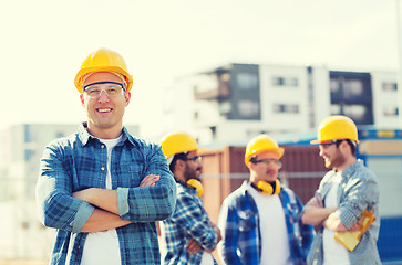 Image showing group of smiling builders in hardhats outdoors