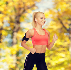 Image showing sporty woman running with smartphone and earphones