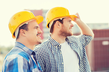 Image showing group of smiling builders in hardhats outdoors