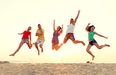 Image showing smiling friends dancing and jumping on beach