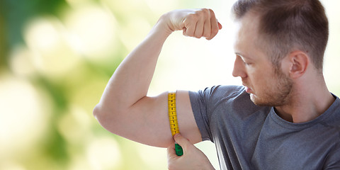 Image showing close up of male hands with tape measuring bicep