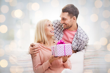 Image showing happy man giving woman present over holiday lights