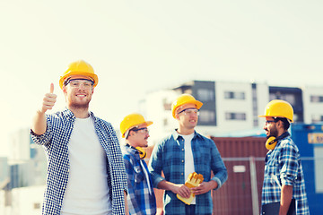 Image showing group of smiling builders in hardhats outdoors