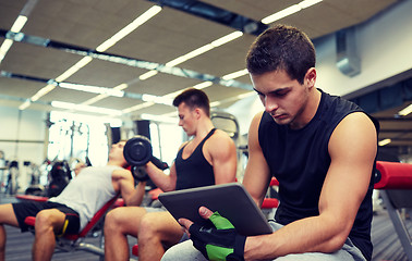 Image showing group of men with tablet pc and dumbbells in gym