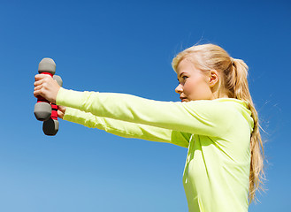 Image showing sporty woman with light dumbbells outdoors