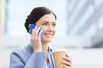 Image showing smiling woman with coffee calling on smartphone