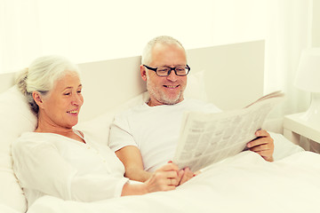 Image showing happy senior couple with newspaper in bed