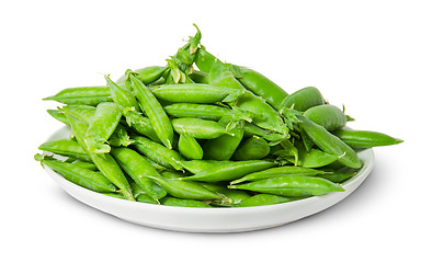 Image showing Big pile of green peas in pods on white plate