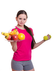 Image showing Beautiful athlete holding a plate of fruit and dumbbell