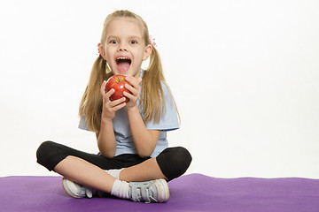 Image showing Cheerful girl athlete eating apple