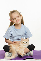 Image showing Thoughtful girl with a cat on her lap sitting the mat