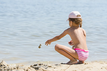 Image showing Girl on the river throws sand in water