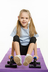 Image showing Six year old girl on a rug engaged with stops for push-ups