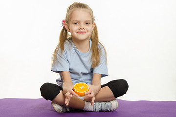 Image showing Six year old girl sitting with orange on sport mat