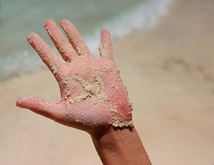 Image showing a white wet sand in sunburned hand