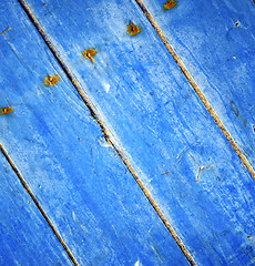 Image showing dirty stripped paint in the blue wood door and rusty nail