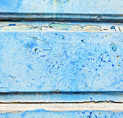 Image showing stripped paint in the blue wood door and rusty nail