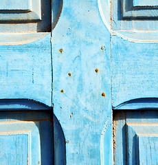 Image showing dirty stripped paint in the blue wood door and rusty nail