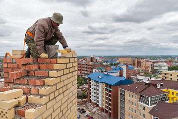 Image showing Bricklayer works on high house construction