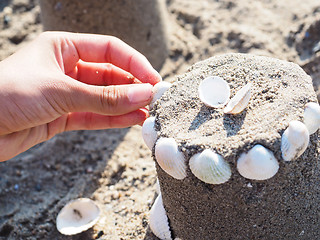 Image showing Person creating a sand castle with white clams