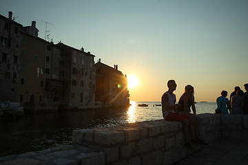 Image showing People sitting on coast at sunset