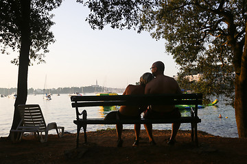Image showing Couple sitting on bench at sunset
