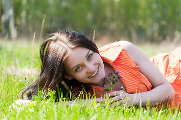 Image showing Pretty girl in orange dress laying on grass