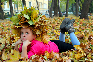 Image showing little girl lying on the yellow leaves