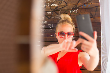 Image showing Young cheerful lady taking selfie.