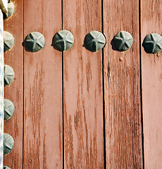 Image showing nail dirty stripped paint in the brown wood door and rusty yello