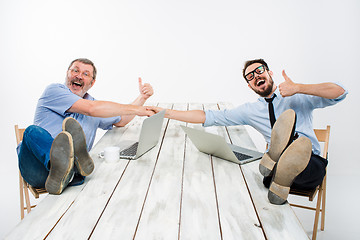 Image showing The two smiling businessmen with legs over table