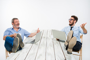 Image showing The two businessmen with legs over table working on laptops