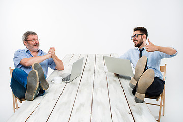 Image showing The two businessmen with legs over table working on laptops