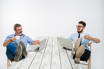 Image showing The two businessmen with legs over table working on laptops