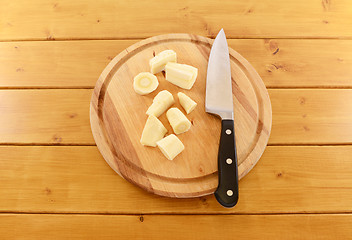 Image showing Chopped parsnip with a kitchen knife on a wooden board 