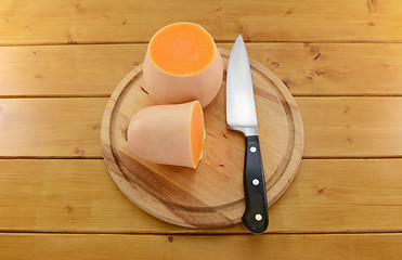 Image showing Butternut squash cut in half with a knife on a wooden board