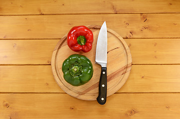 Image showing Red and green peppers with a knife on a chopping board 