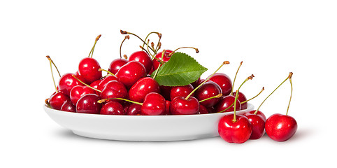 Image showing Sweet cherries with leaf on white plate and three near