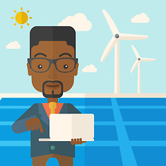 Image showing African man with laptop in solar panel.