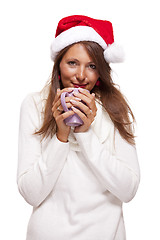 Image showing Cold young woman in a Santa hat sipping coffee tea