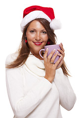 Image showing Cold young woman in a Santa hat sipping coffee tea