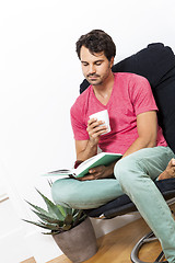 Image showing Man Sitting on Chair with Book and a Drink