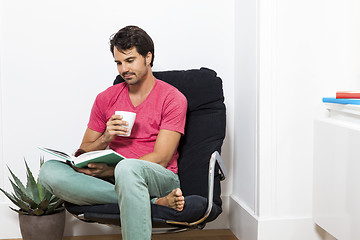 Image showing Man Sitting on Chair with Book and a Drink